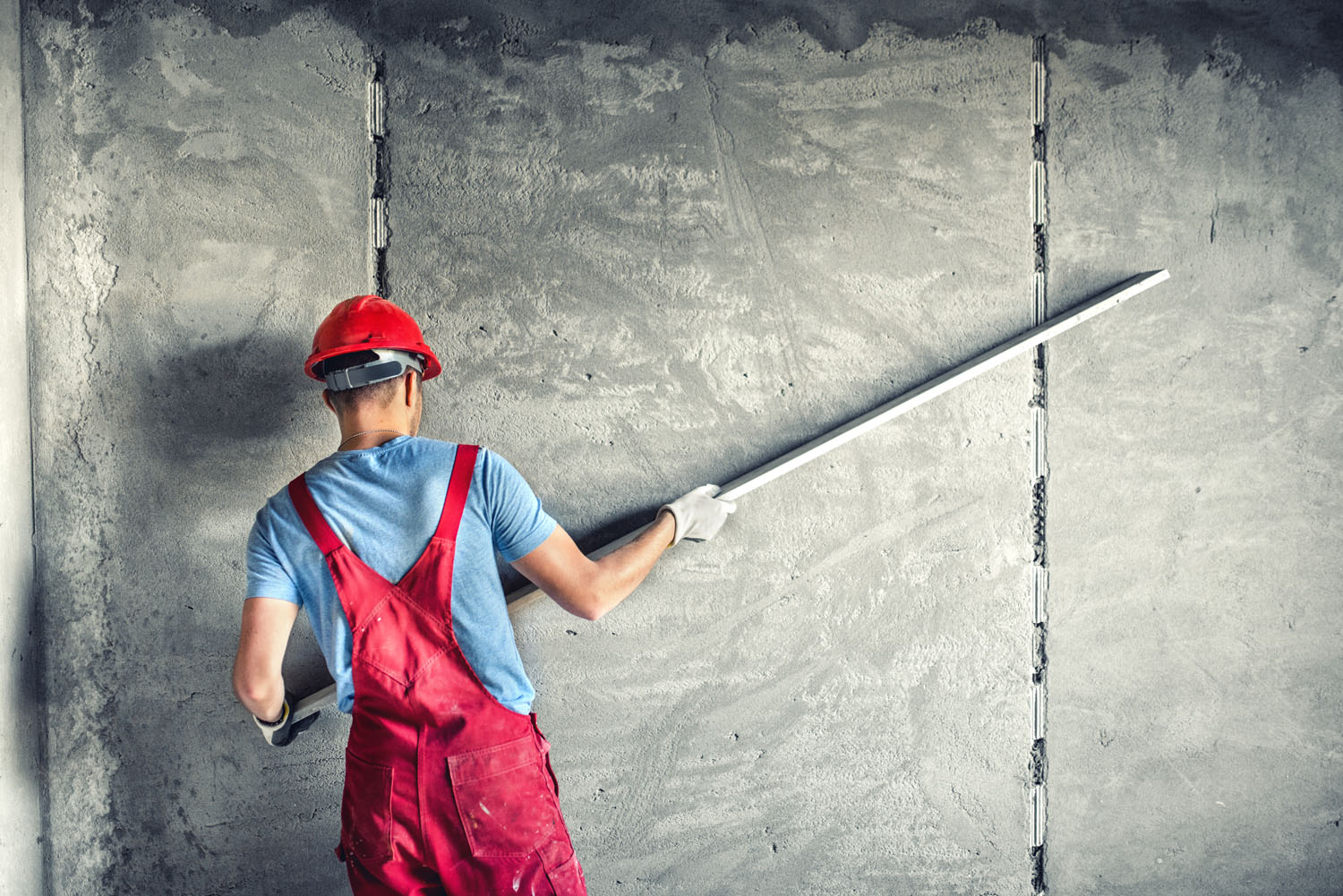 industrial worker with plastering tools renovating a house. builder worker plastering facade industrial building with leveler